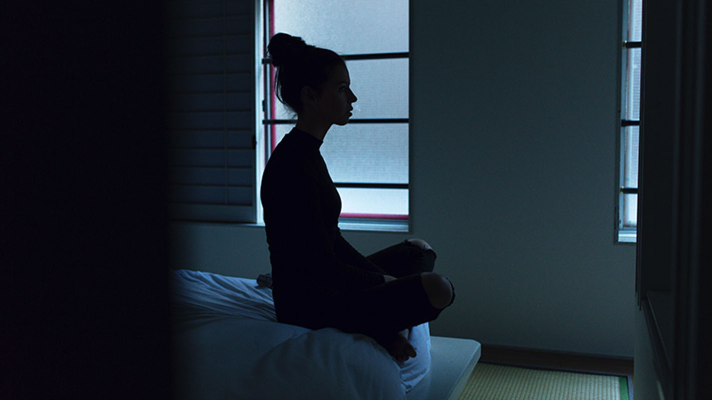 Woman meditating on bed, meditation for dealing with sadness and depression